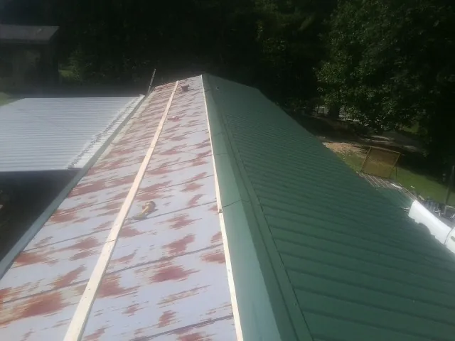 Old rusted panels beside newly installed green metal roofing — Wind Damage Roof Repair by Roofing Brothers in Frisco