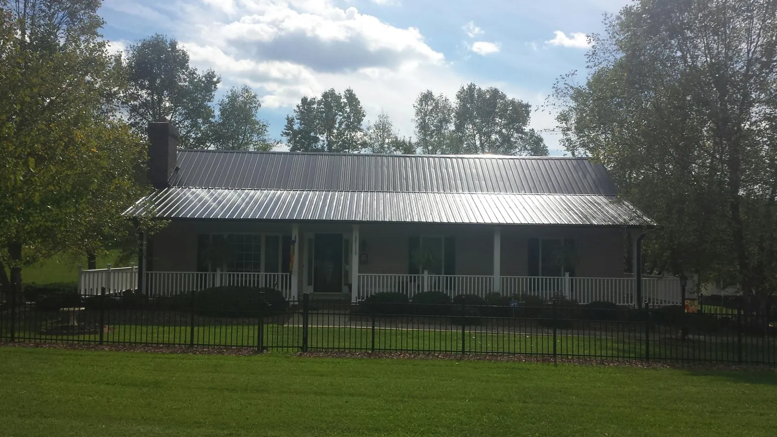 Gray metal roof on a brick ranch with a full width front porch — Gutter Guard Installation work by our crew in Frisco
