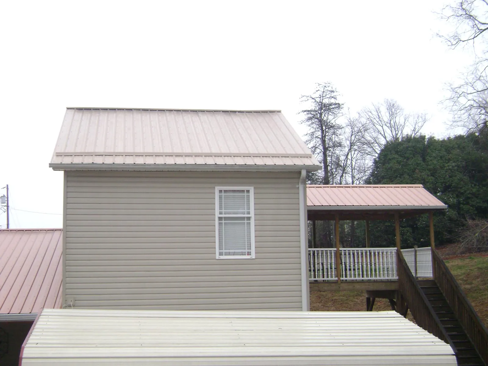 Tan metal roofs on a two story addition and attached porch, from a Roof Replacement job in Frisco